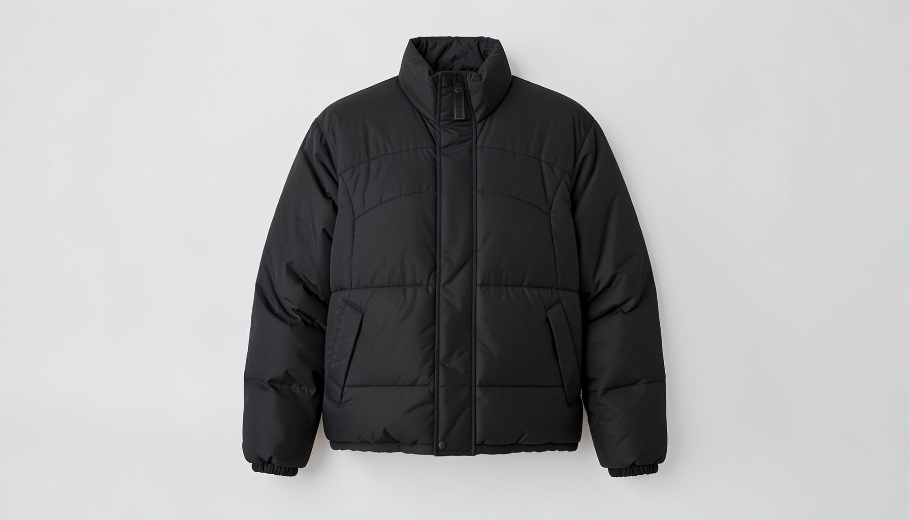 Black nylon oversized puffer jacket with curved panel detailing against a light grey background