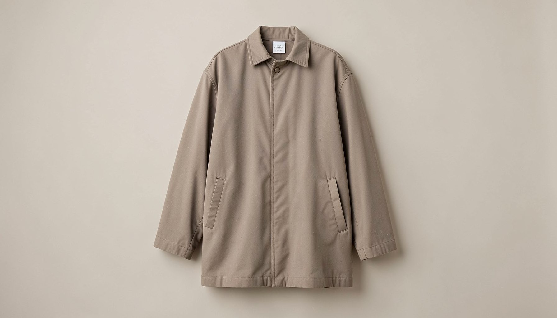 Stone-coloured oversized longline jacket with piped seam detailing on a neutral backdrop