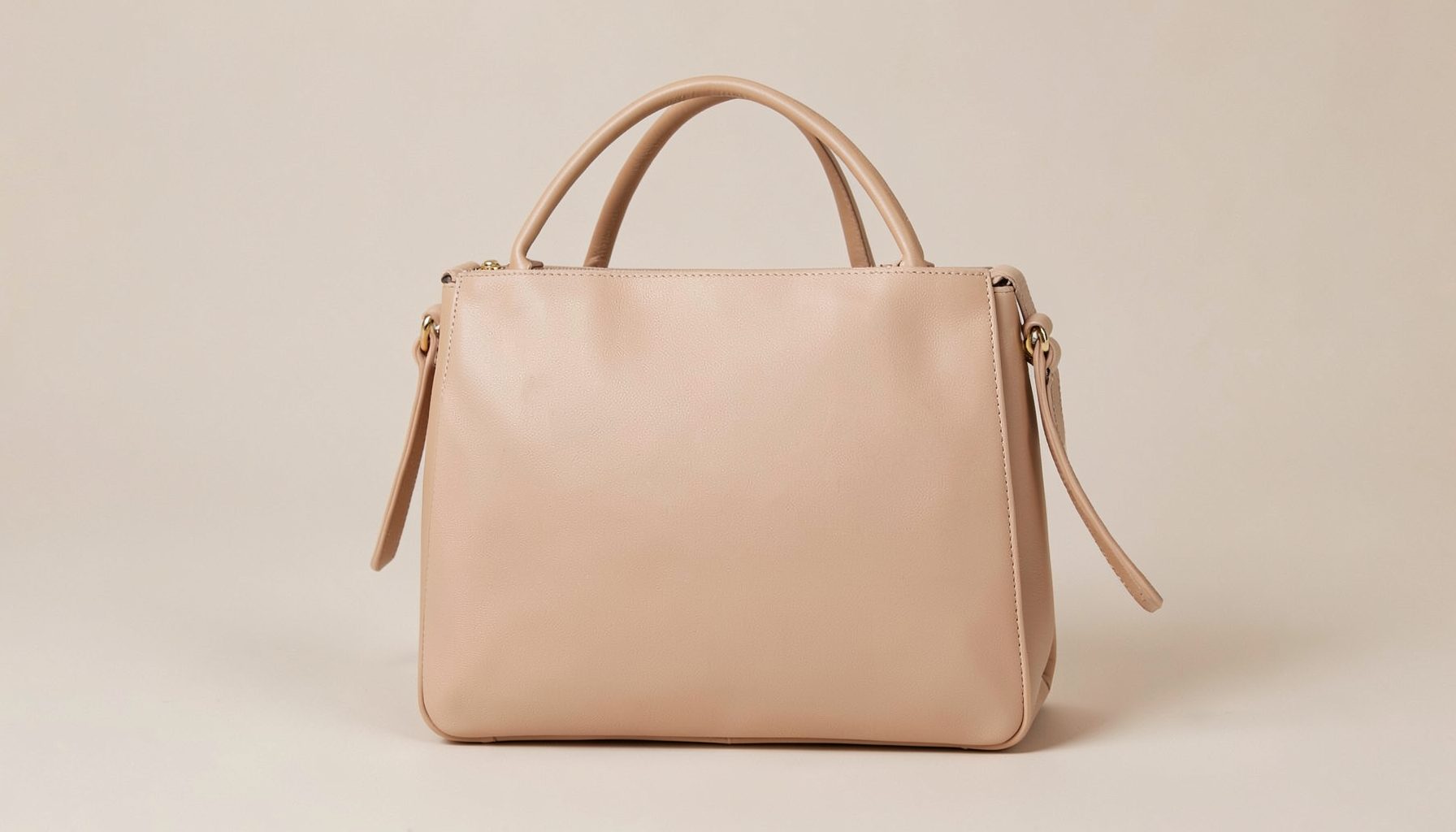 A stylish women's handbag and purse displayed on a neutral background, in soft beige and tan tones