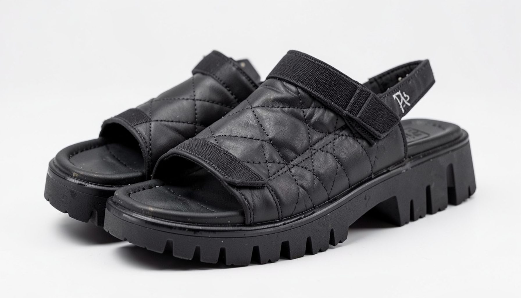Black quilted velcro-strap cleated-sole sandals with a chunky tread, edgy and utilitarian