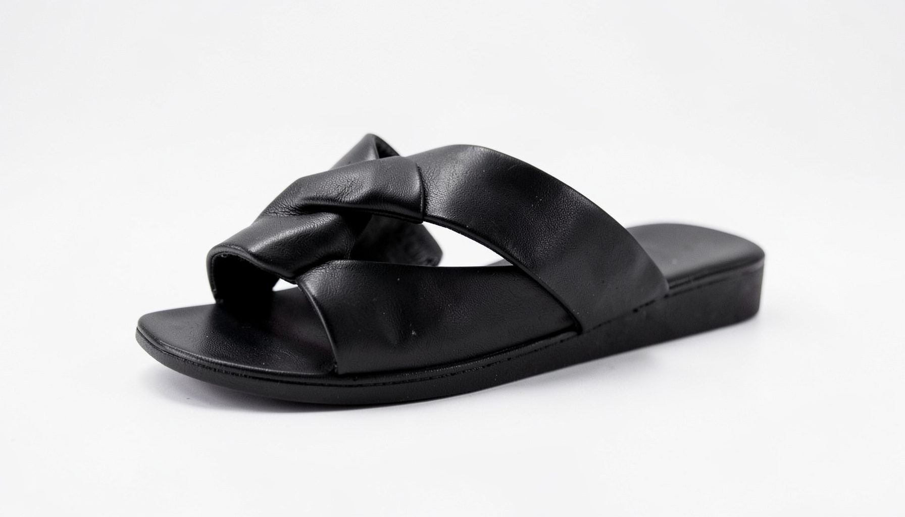 Black twist-strap sandals with a minimalist flat sole, sleek and versatile