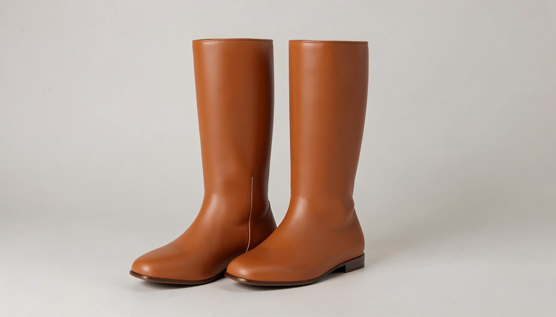 Matte PU knee-high flat-heeled boots in warm toffee brown with a sleek silhouette against a neutral studio background